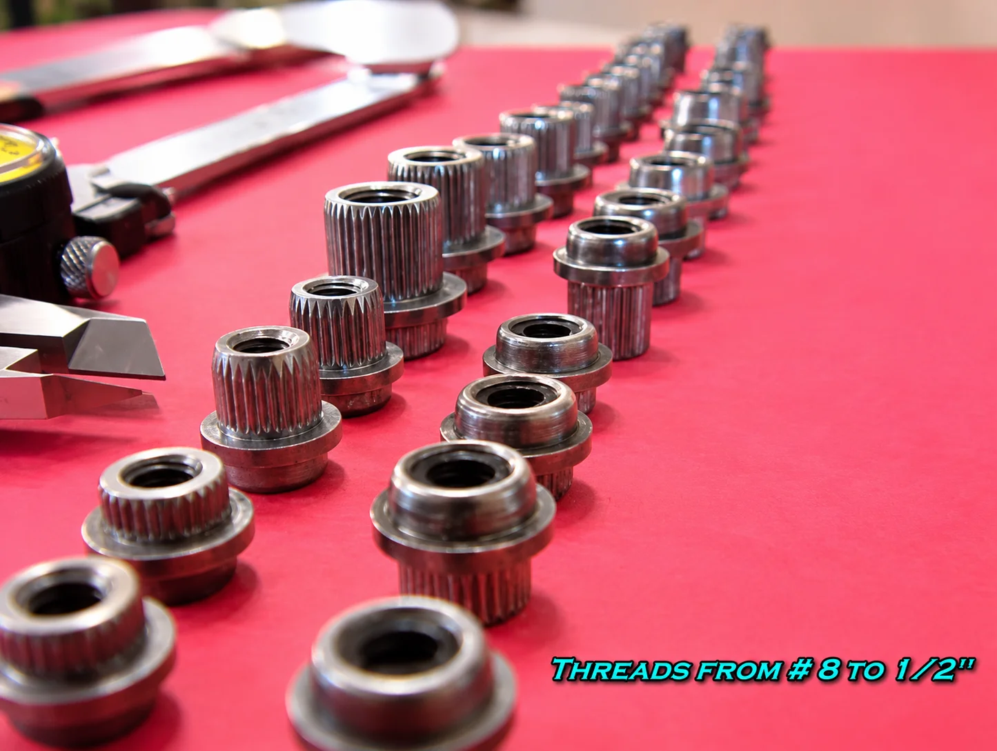 赤い背景に並べられた様々なサイズのスプラインナットナイロンインサートロックナット製品群、ノギスと工具とともに撮影